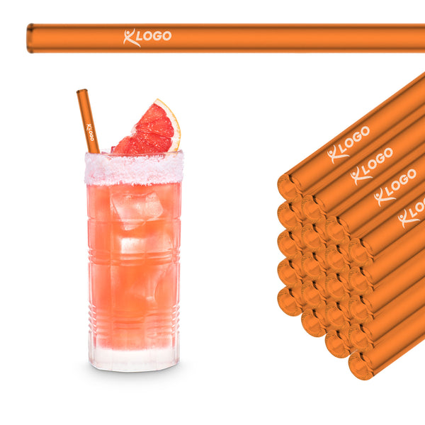 Neonorange 20 cm HALM Glasstrohhalme mit Beispiel-Logogravur im Stapel neben einem Pink Paloma im Longdrinkglas